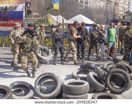 KYIV, UKRAINE - Aug 7, 2014: A police officer takes the tyer out of the barricades. Activists and police have clashed in Ukrainian capital\'s center after communal workers tried to dismantle camp
