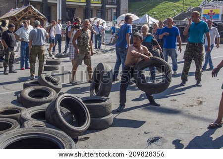 KYIV, UKRAINE - Aug 7, 2014: Activists throw tires in the fire. -- Activists and police have clashed in the Ukrainian capital\'s center after communal workers tried to dismantle the camp.