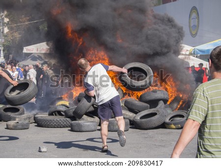 KYIV, UKRAINE - Aug 7, 2014: Activists throw tires in the fire. -- Activists and police have clashed in the Ukrainian capital's center after communal workers tried to dismantle the camp.