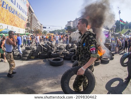 KYIV, UKRAINE - Aug 7, 2014: Activists wearing tire to fire. -- Activists and police have clashed in the Ukrainian capital\'s center after communal workers tried to dismantle the camp.