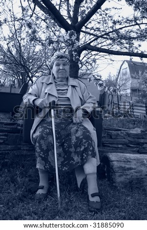 Black and white portrat of old-age woman, who seating in a blossoming garden