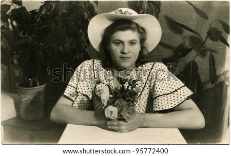 Soviet Union - circa 1950s: Portrait of a woman in a hat on the background of indoor plants, circa 1950s