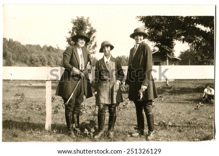 CANADA - CIRCA 1930s: Reproduction of an antique photo shows three women in riding costume posing near the fence corral for horses