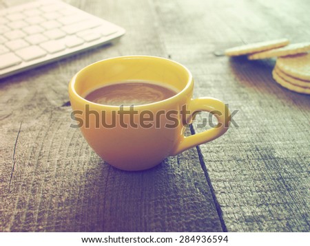Computer keyboard, cup of coffee and biscuits on old weathering wooden table. Grunge style