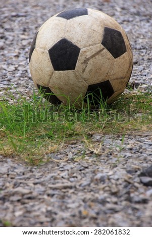 An old football or soccer ball on crushed gravel yard.
