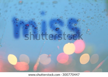 Rain drops with miss text write on window with light bokeh, rainy season abstract background.