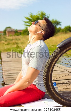 young man sitting at the beach with map and resting after bicycle ride