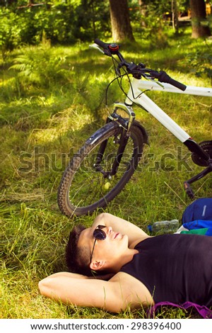 young man lying in the park and resting after bicycle ride
