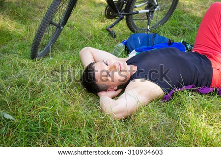 young man lying in the park and resting after bicycle ride