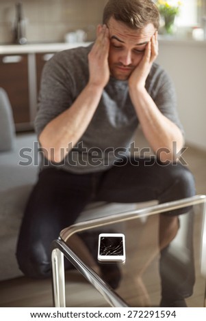 Worried man looking at broken smart phone