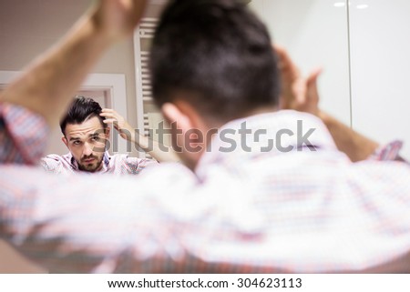 Young man applying hair cosmetics during hair caring