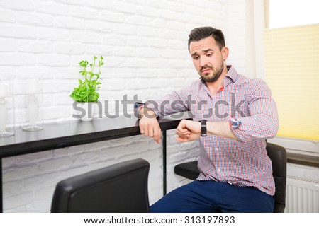 Young man looking at his watch with confused face