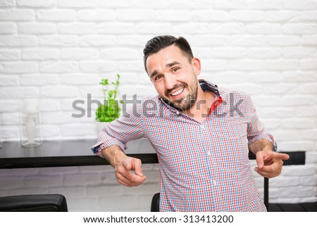 Happy man in casual shirt pointing his fingers at camera