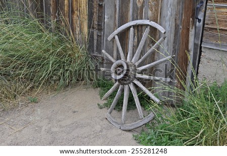 A weathered, broken old wagon wheel leaning against a barn on a farm in Colorado.