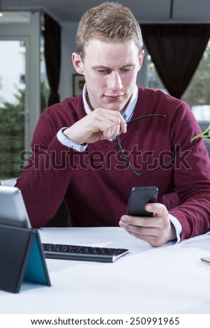 young businessman is looking the mobile phone on a working lunch while is waiting for his meal at a restaurant - focus on the man face