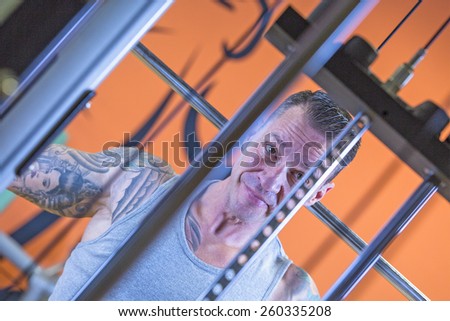portrait of a man making behind the neck lateral pull downs - dorsal exercise - at the gym - focus on the man face
