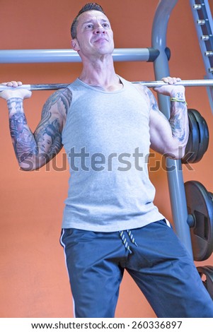man making barbell squat - leg exercise - at the gym - start exercise - focus on the man face