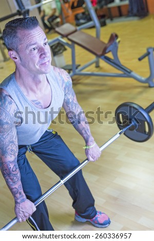 man making bent over barbell row - dorsal exercise - at the gym - start exercise - focus on the man face
