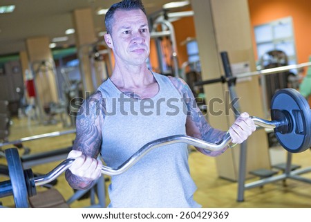 young man making standing bar curl biceps exercise - inside grip - at the gym - finish exercise - focus on the man face