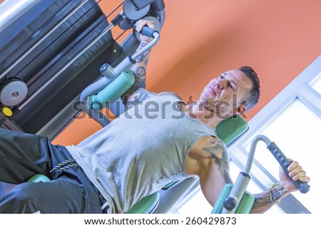 man making pec deck fly - chest exercise - at the gym - start exercise - focus on the man face