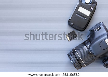 top view of a desktop of a photographer consisting on a camera, a photometer and a memory card on a grey desk background - suitable for copy space