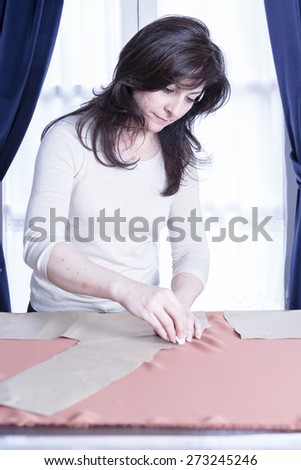 dressmaker marking a fabric with a chalk at her sewing atelier - focus on the left eye