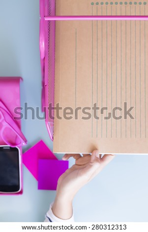 top view of a hand of a woman taking a folder from a letter tray on a working desk - focus on the thumb