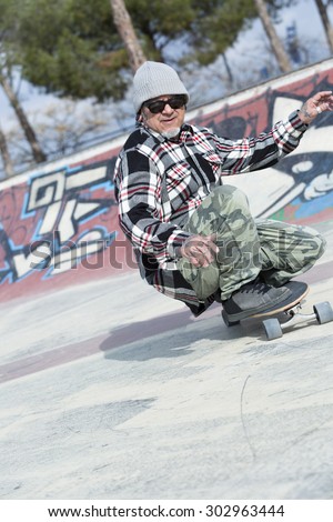 old man skater is skating crouched with a skateboard on a skating park - focus n the face