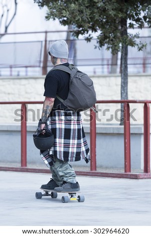 old man skater is leaving a skate park with his skateboard after a skating session - focus on the head