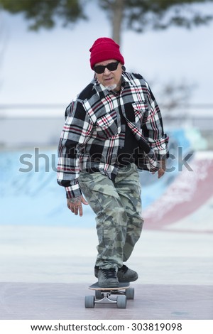 old man skater is skating with his skateboard on a skating park - focus on the face