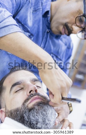 relaxed costumer on a beard shaving session on a barber shop - focus on the customer face