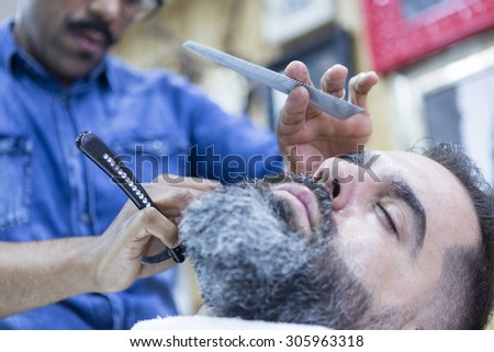 closeup of a customer on a beard shaving session in a barber shop - focus on the customer eye