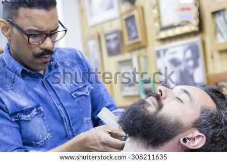closeup of a young customer on a beard shaving session in a barber shop - focus on the customer eye