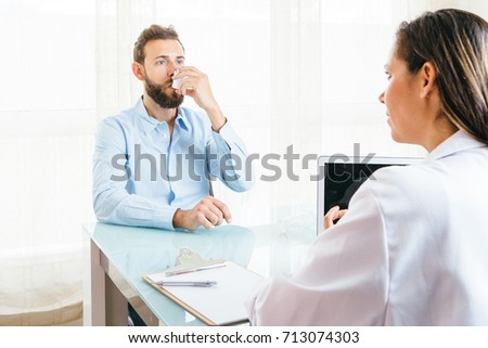 Male patient is inhaling a medicament from an aerosol inhaler in front o a female doctor at  her office Imagine de stoc © 