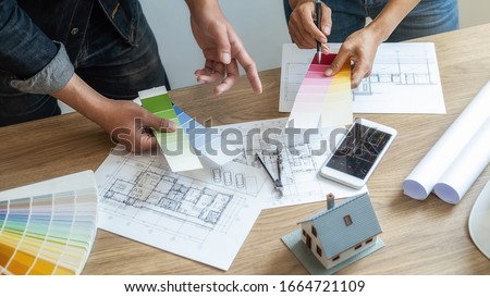 Interior designer and Architect choosing color in color swatch samples chart for house coloring selection in office with blueprint. Construction concept. 商業照片 © 