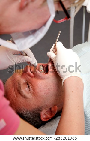 man is getting his tooth checked at the dentist\'s office