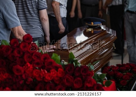 People came to say goodbye to a deceased relative of a military officer in the church before the burial, carrying flowers and touching the wooden brown coffin. on which lies a military cap Stock foto © 