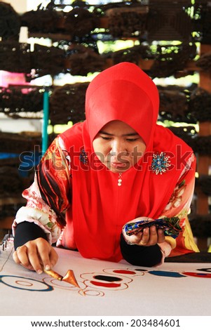 TERENGGANU, MALAYSIA - APRIL16,2014 - An artist carefully trace on a traditional batik at Noor Arfa Craft Complex, Terengganu, Malaysia
