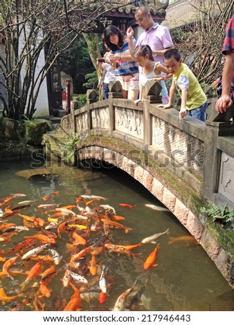 CHENGDU, CHINA  - JULY 29, 2012 : Unidentified people feeding goldfish at Ancient Statue of Guan Yu, Wuhou Memorial, Three Kingdoms, Temple, Chengdu, Sichuan, China.