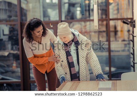 What would you like. Positive friendly woman showing her kindness while asking an elderly woman what she wants 商業照片 © 