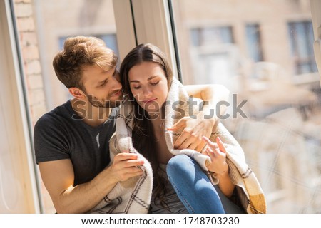 Happiness. Young bearded man hugging his wife and looking contented