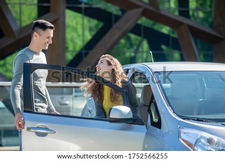 Test drive. Young pretty woman opening the car door and talking to the young man Zdjęcia stock © 