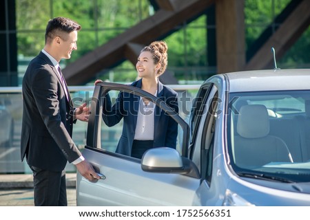 Polite behavior. Polite young man in a suit opening a car door for a pretty smiling woman. Zdjęcia stock © 