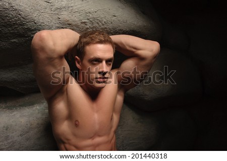 Strong muscular man athlete atlant holding huge stone. Half length portrait. Symbol of power, burden