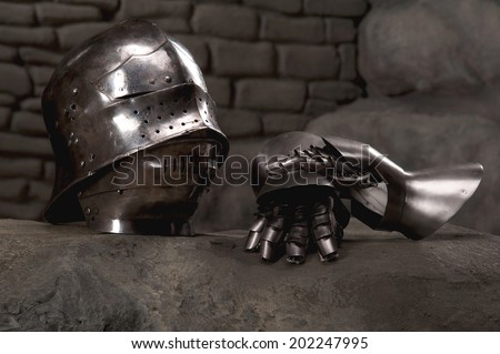 Closeup of knight armor helmet and gloves on the dark stone wall background