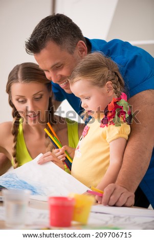 Half-length sideview portrait of lovely happy family drawing and painting at home together, laughing and having fun
