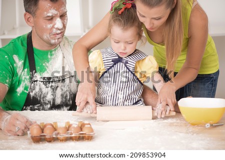 Closeup portrait of cute little daughter with handsome father and beautiful mother cooking pastry, working with rolling pin