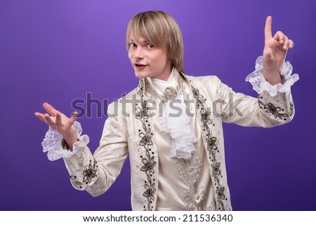 Half-length portrait of handsome fair-haired juggler wearing great white costume opening us the secret of his tricks. Isolated on violet background