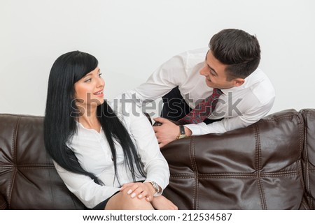Half-length Portrait of young businessman  and his pretty colleague woman smiling to each other in office interior