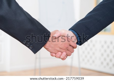 Close-up photo of hands of businessmen in suits handshaking after signing the contract in office interior With copy place